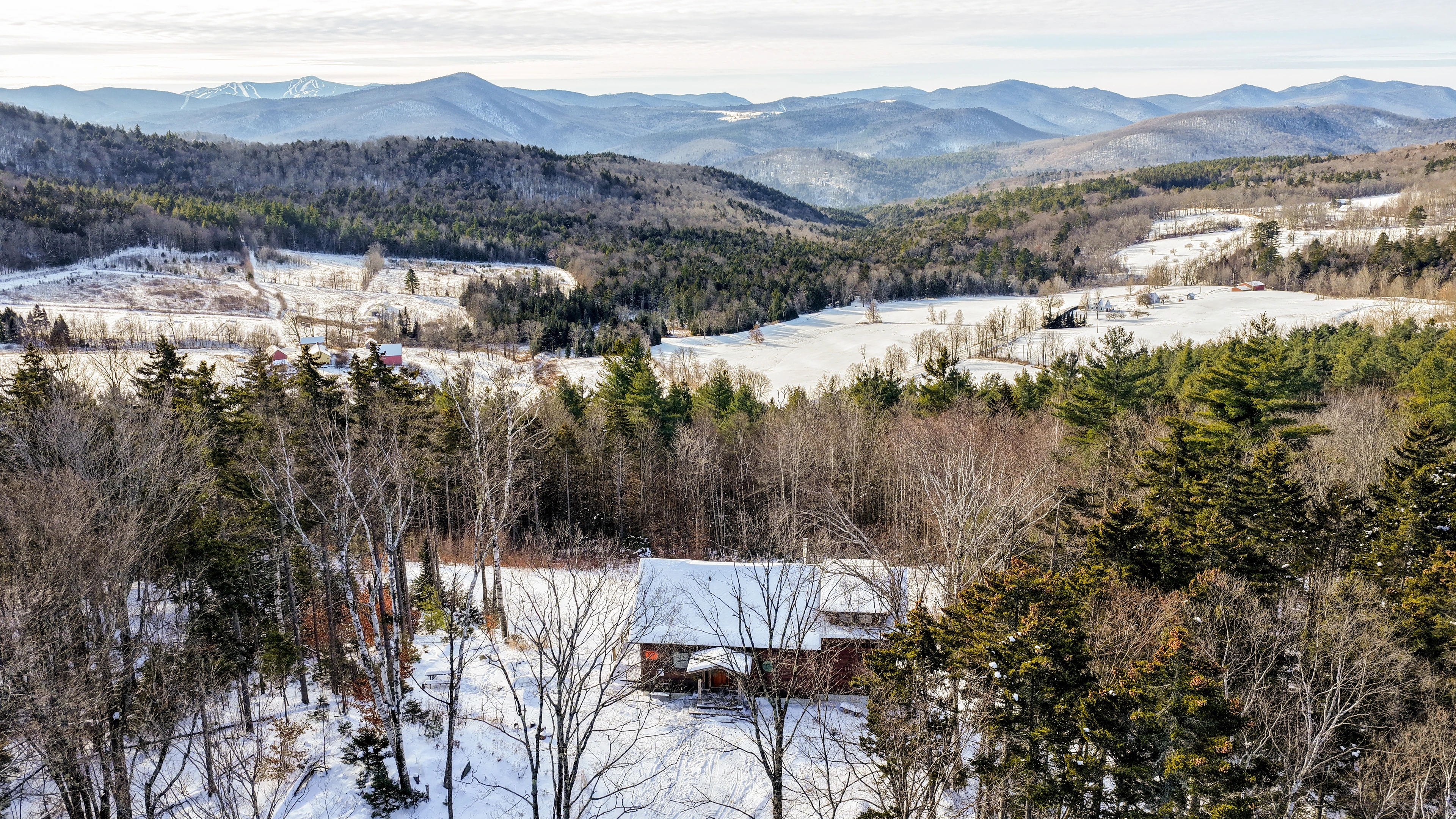 Winter aerial of a woodland home and layered Green Mountain ridgelines at Stockbridge, Vermont.