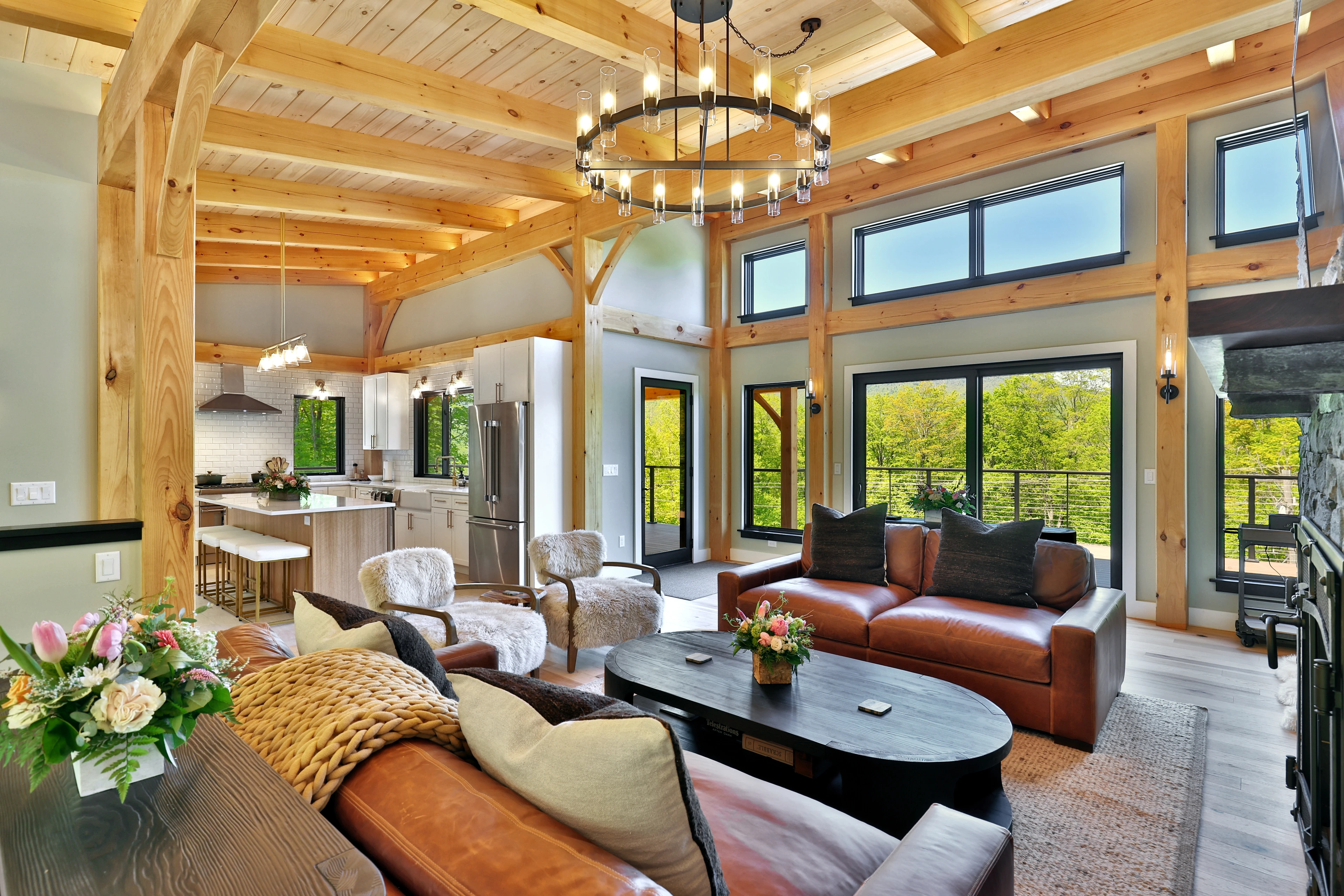 Vaulted timber frame great room with tall windows and a stone fireplace at Killington, Vermont.