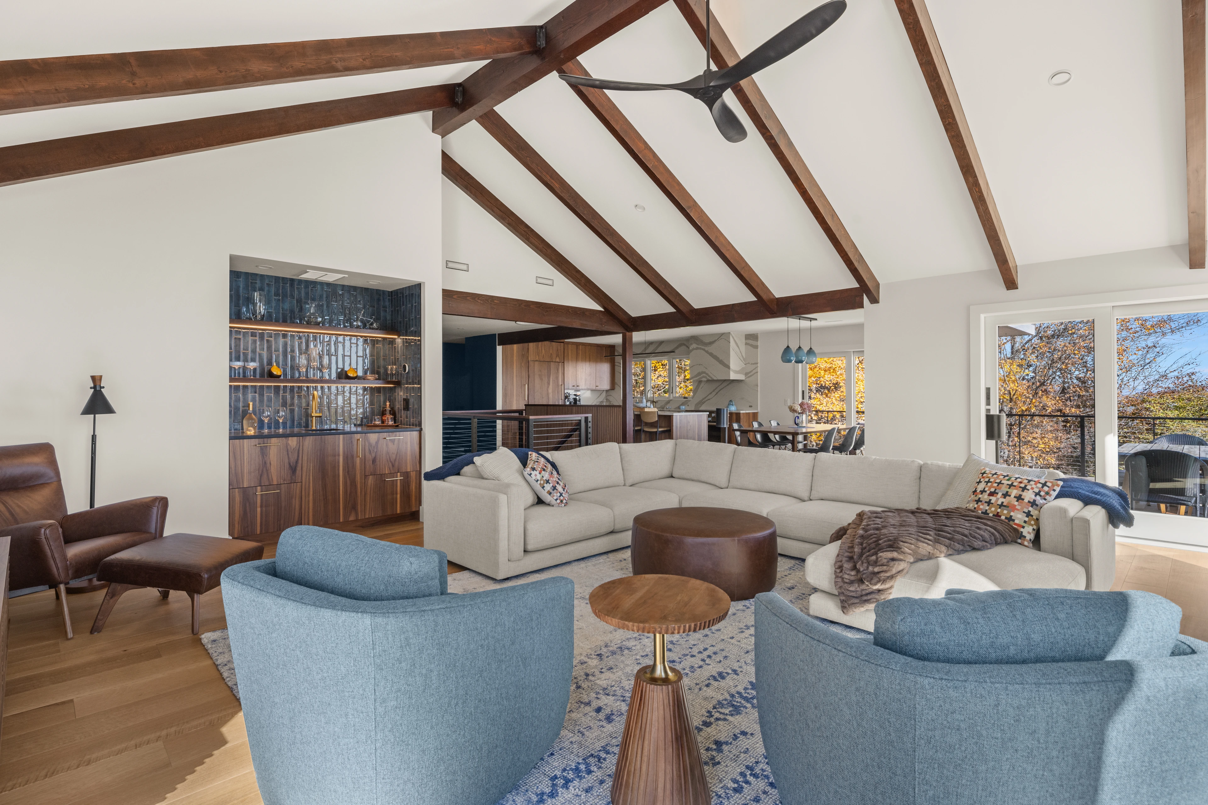 Great room with exposed beams, blue chairs and an adjoining bar at Quechee, Vermont.