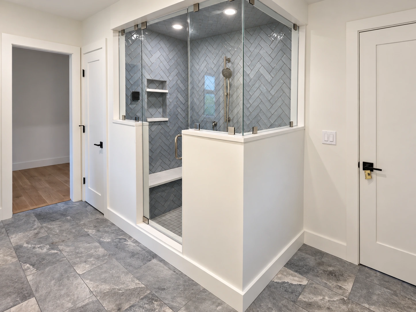 Glass-enclosed shower with gray tile, white trim and a stone-pattern floor in Quechee.