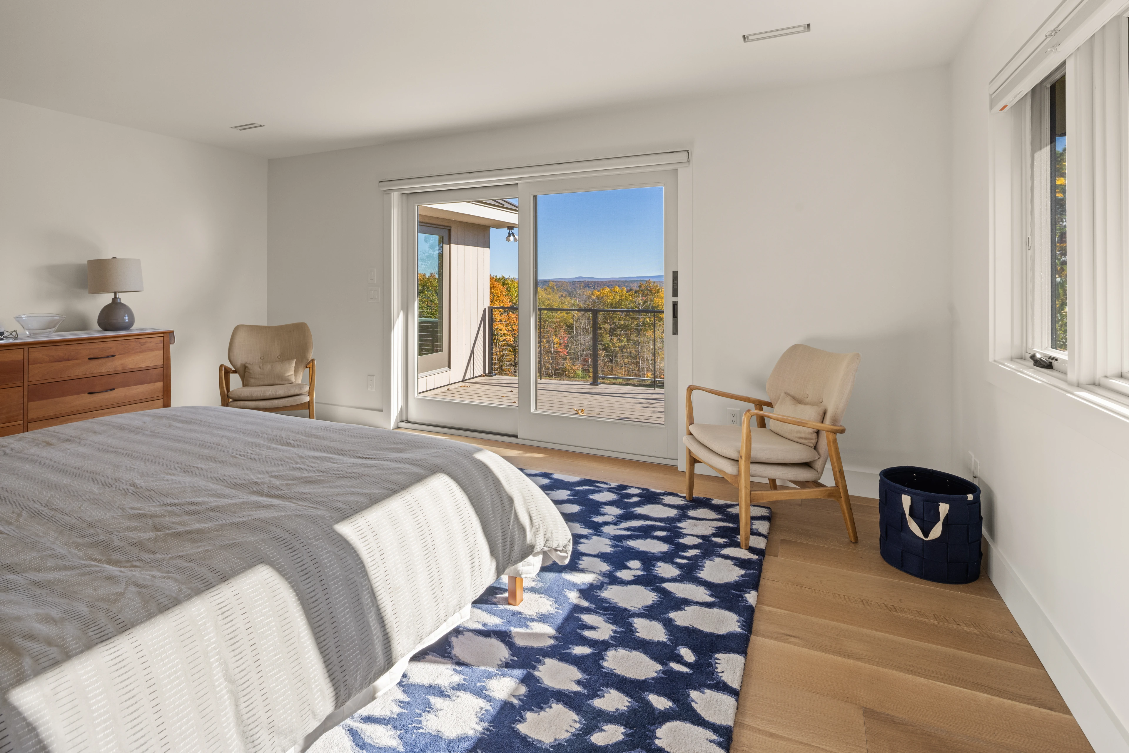 Light-filled bedroom opening toward a deck and autumn views in Quechee.