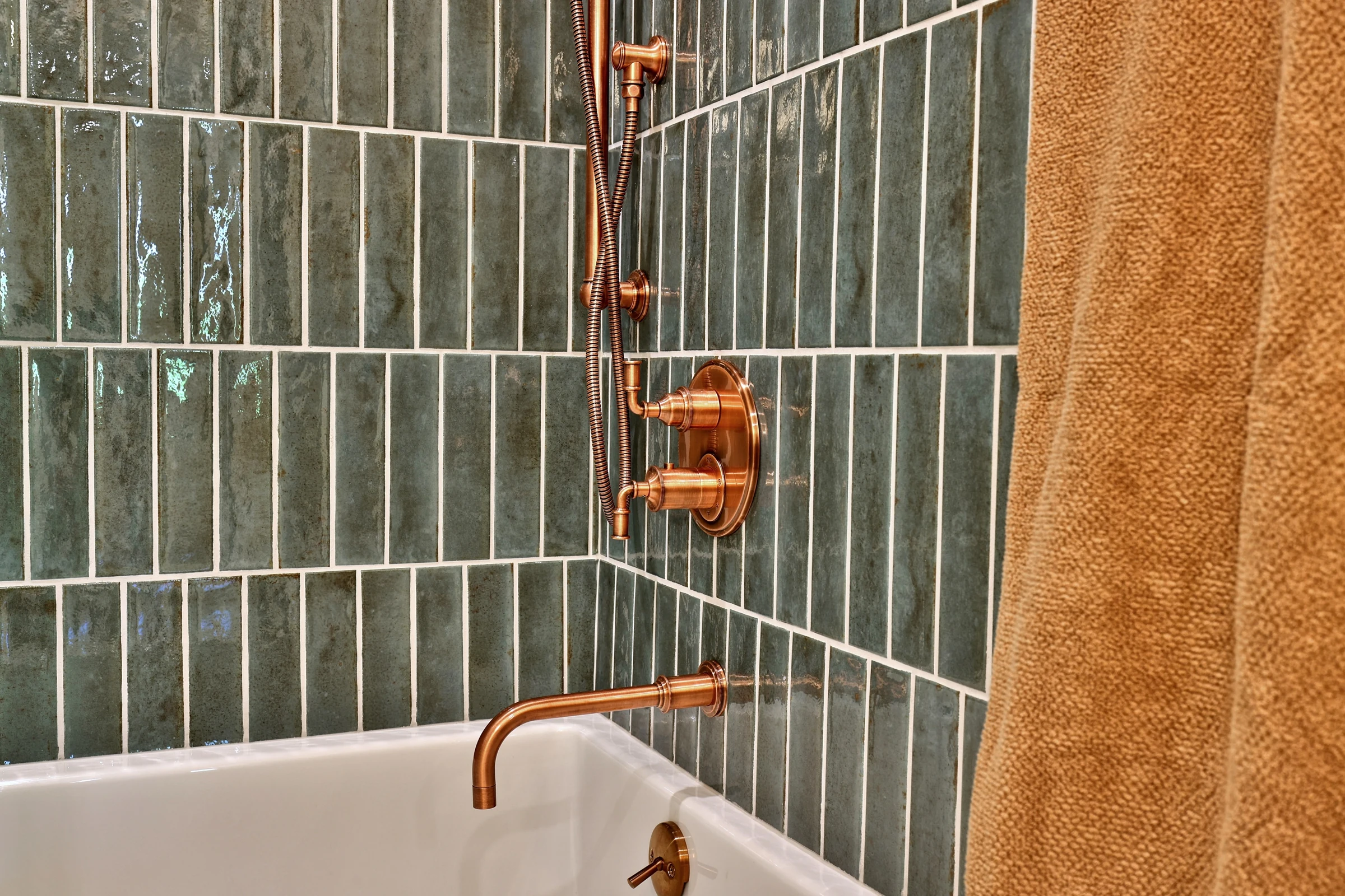 Glossy green vertical tile and copper shower fixtures in the Killington timber frame home.