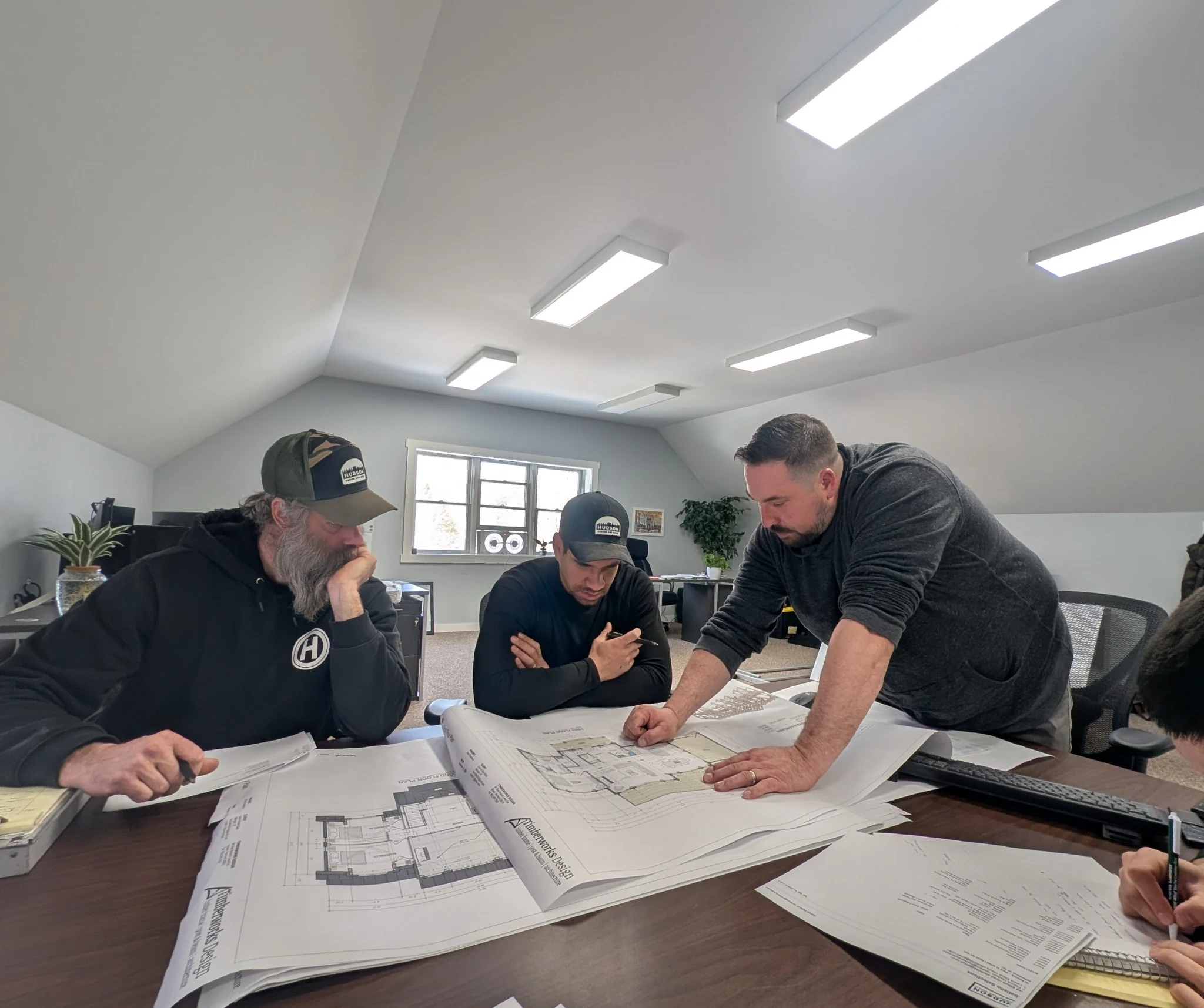 Hudson teammates gathered around architectural drawings, reviewing the plans together.