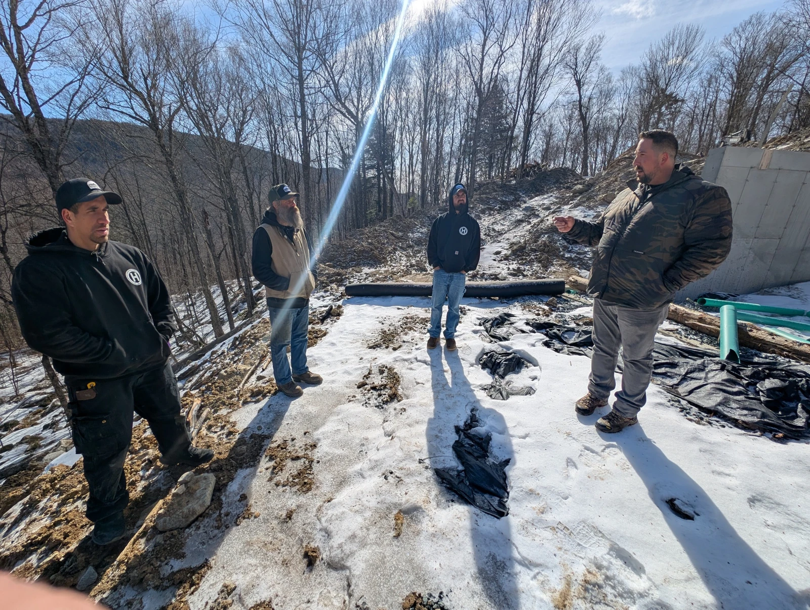 Four Hudson teammates discussing the work at a snowy mountain construction site.