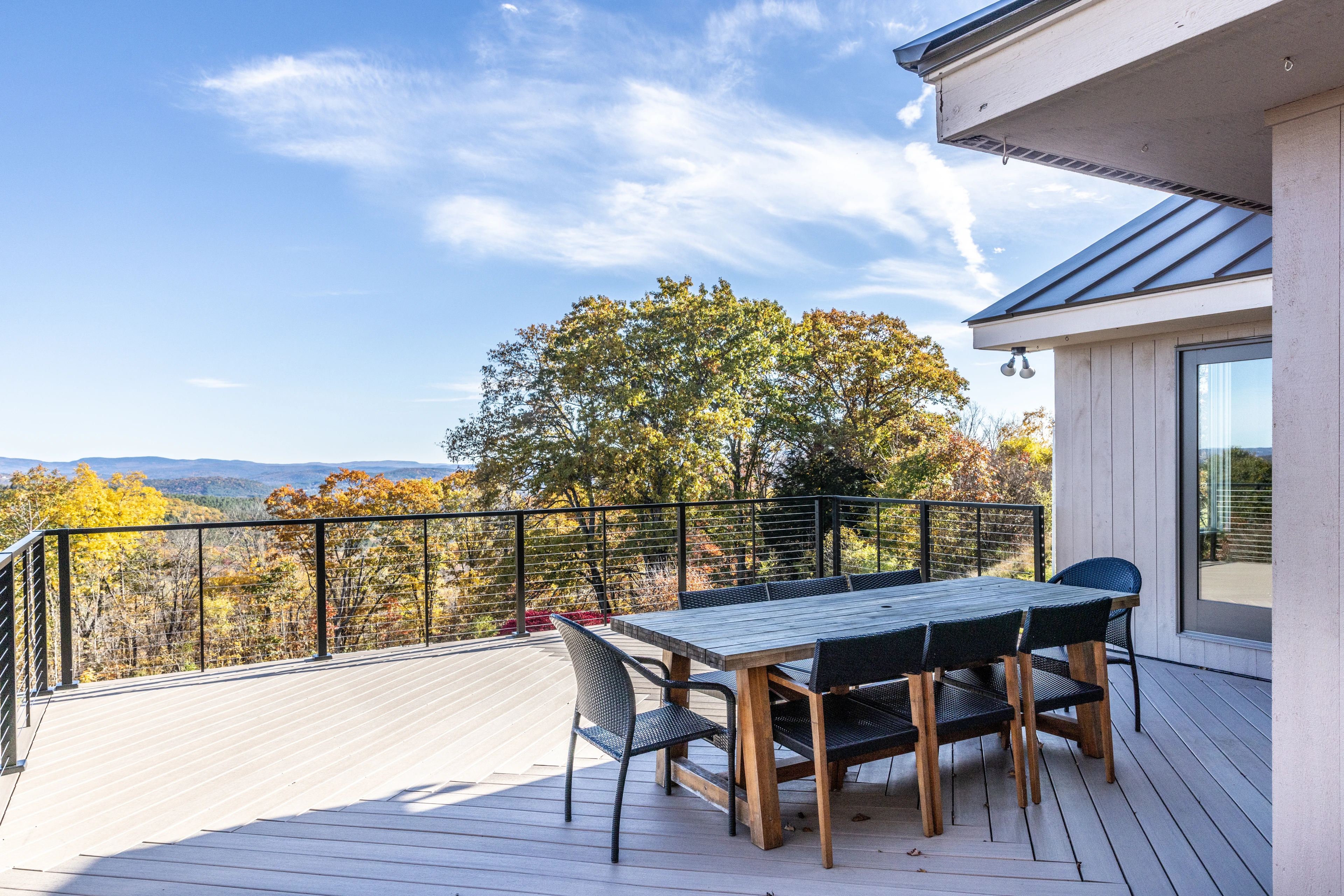 Deck with outdoor dining, dark railing and autumn hills at Quechee, Vermont.