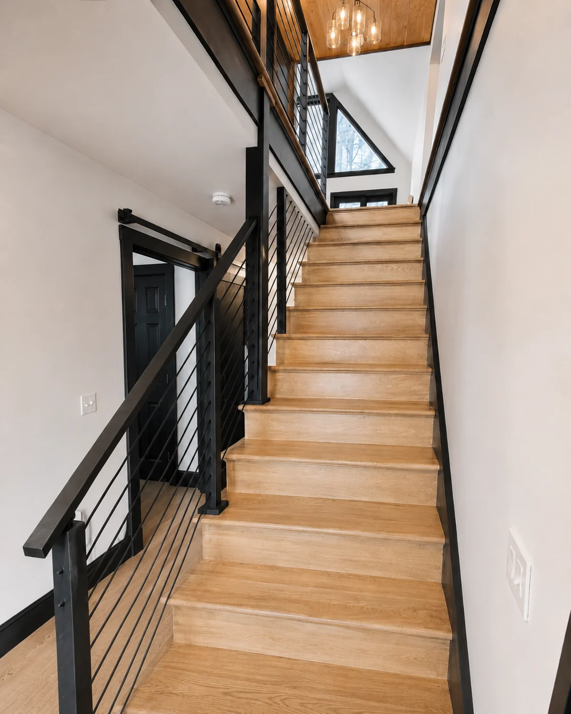 Custom wood staircase with dark railings and an open stairwell in a Hudson Design and Build renovation on South Street, Woodstock, Vermont.