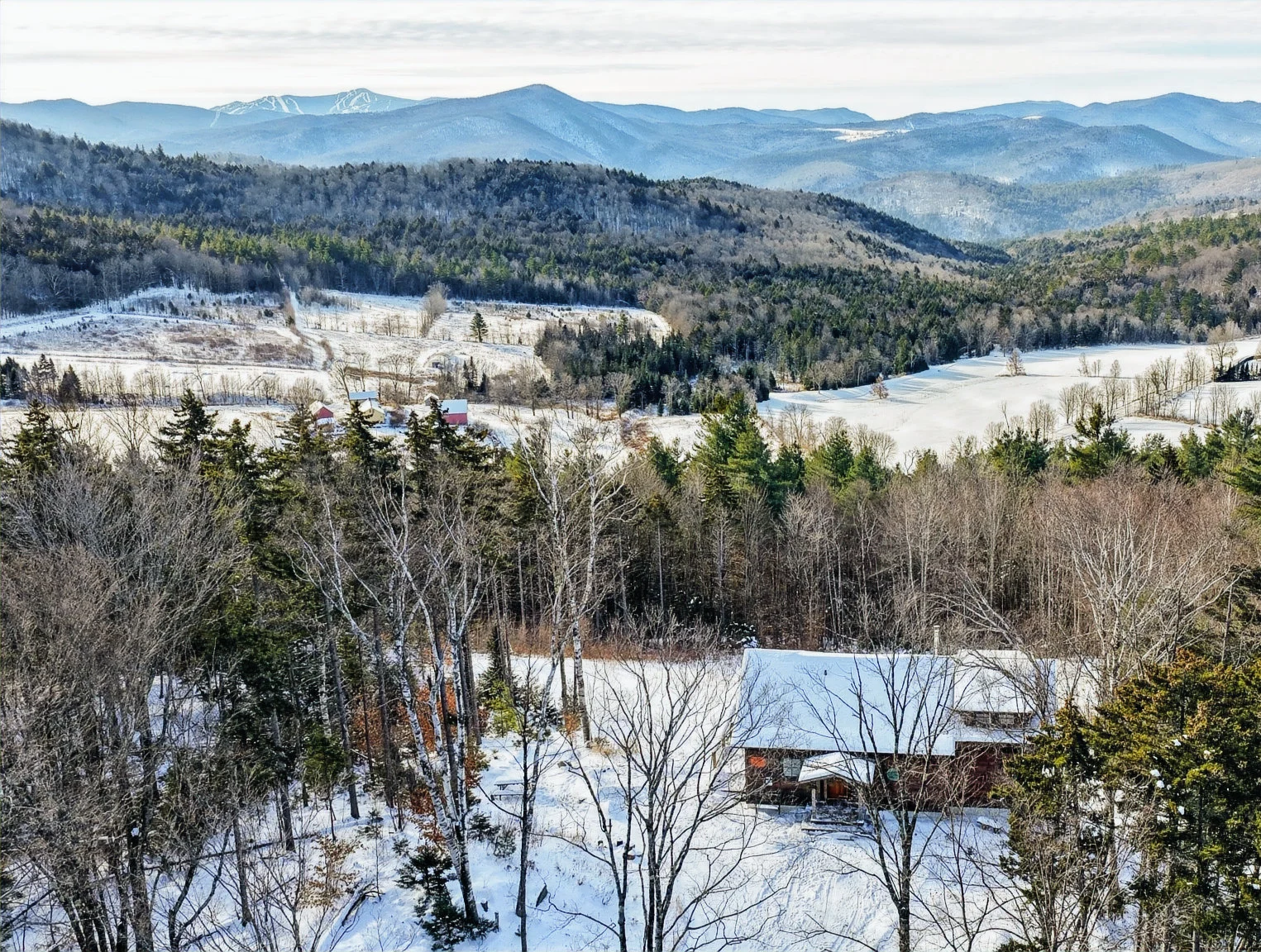 Aerial view of a Hudson Design and Build ski home among snowy woodland and mountain ridges near Killington, Vermont.