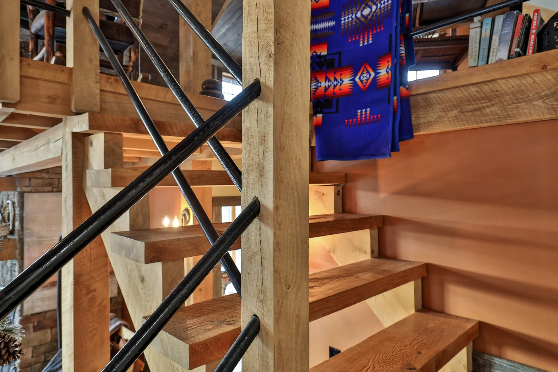 Wood stair treads and timber framing with black metal railing and shelving above.