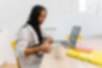 Neurodivergent individual writing notes in a notebook beside a laptop in a calm workspace, representing communication accommodations that support clarity, processing, and accessible information exchange in therapy and coaching