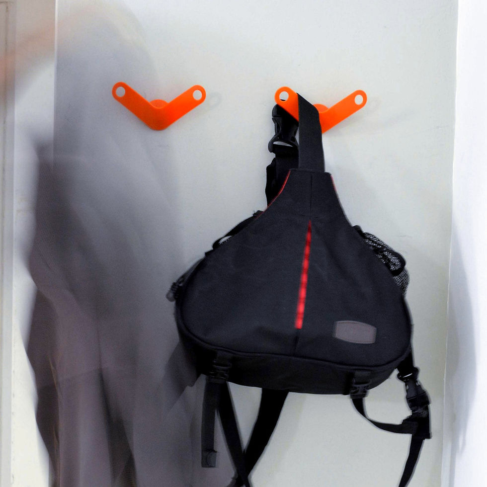 perchero de pared color naranja en uso con mochilas y sacos sobre pared gris