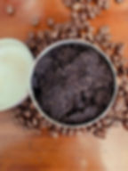 one open tin, screw top lid is off, open tin showing coffee scrub sitting on a pile of coffee beans natural background