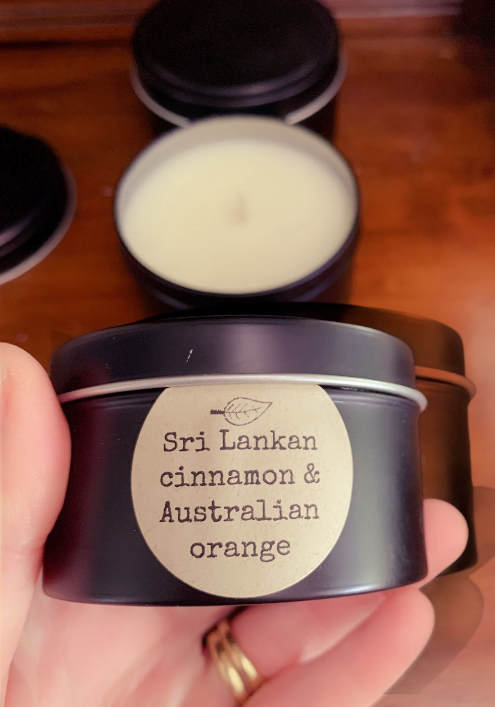 A black tin being held up to show the size of the tin fits into a hand label reads Sri Lankan cinnamon & Australian orange