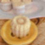 a single shampoo bar flower shaped sits on a yellow ceramic soap dish in the background are more of the same bars