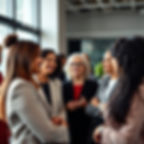 An intergenerational group of diverse professional women engage in conversation in a well