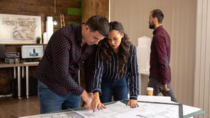 Construction professionals reviewing technical drawings and environmental product data during specification planning