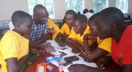 Samson demonstrates to students how to connect a LED bulb on a breadboard in a Yiya engineering class.jpeg