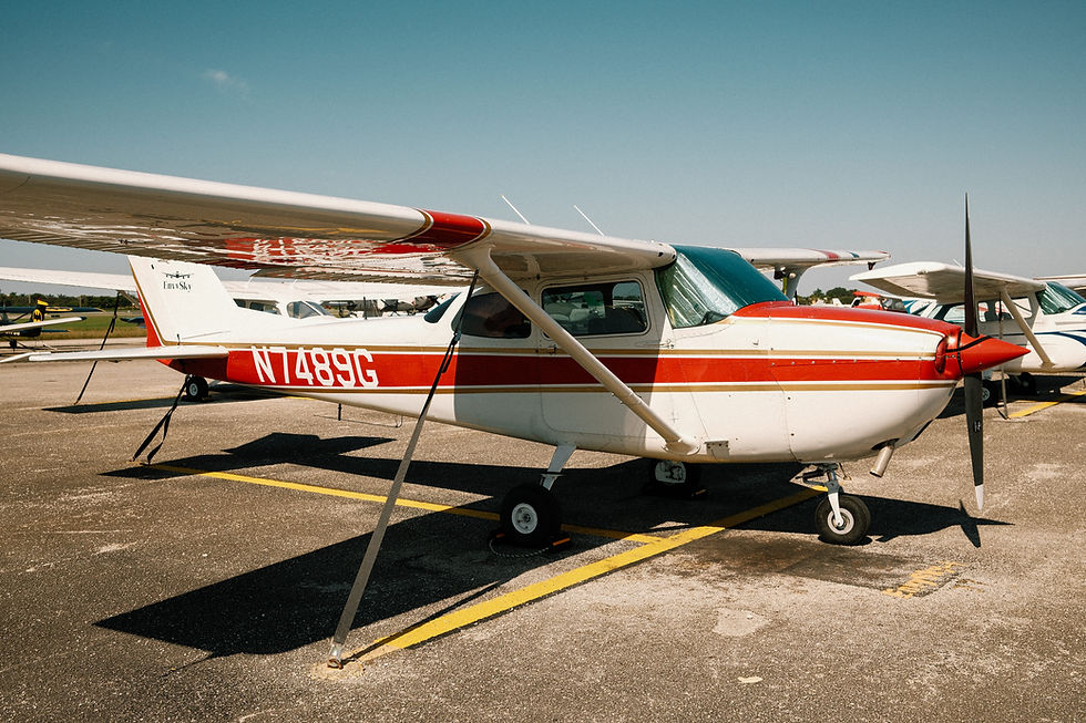 Red and white single-engine training aircraft parked on the flight line under the sun.