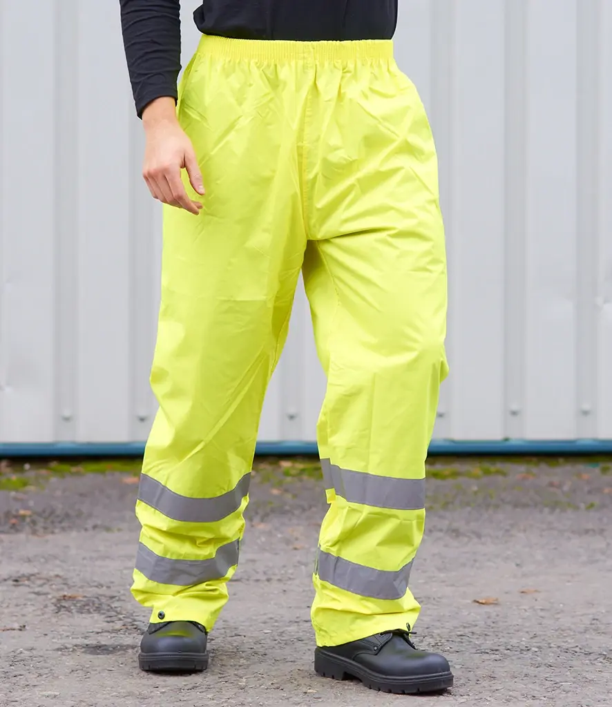 Person wearing bright yellow work pants with reflective stripes, The Workwear Hub