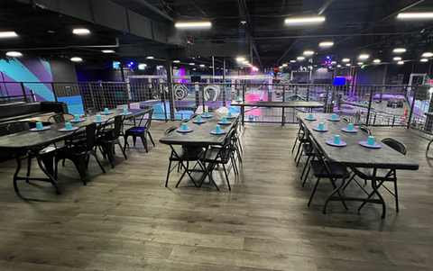 The balcony area set up for a party. Blue and purple cups, napkins, and plates are set up on the table. 