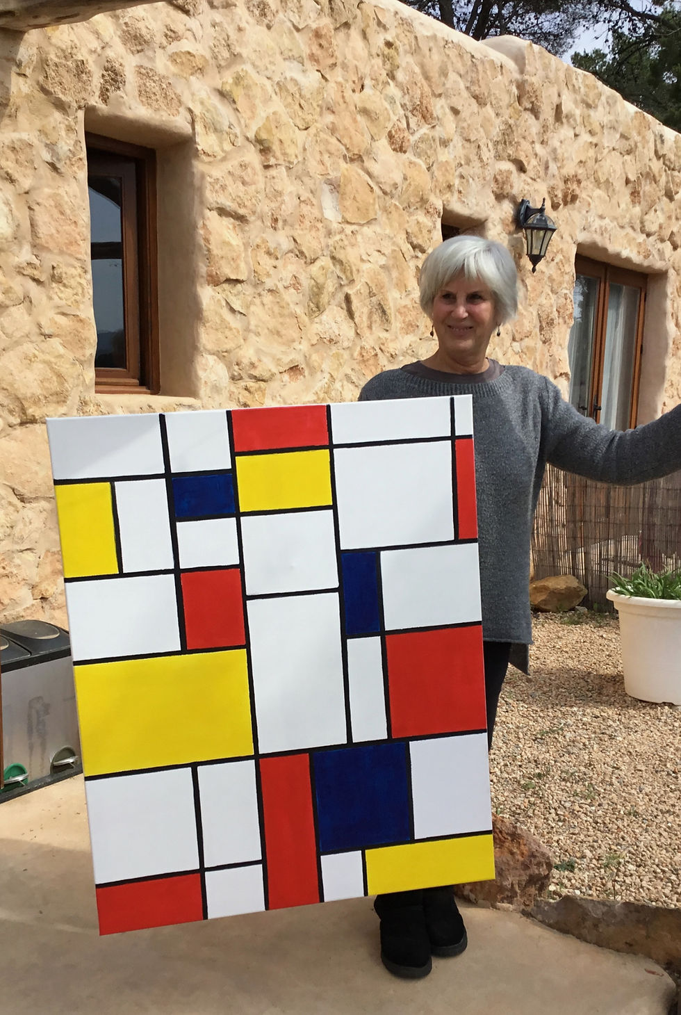 The artist displays the finished Mondrian-inspired grid painting in black, white, red, yellow and blue.