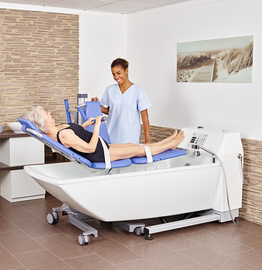 Pflegekraft hilft Seniorin in eine barrierefreie Sitzbadewanne