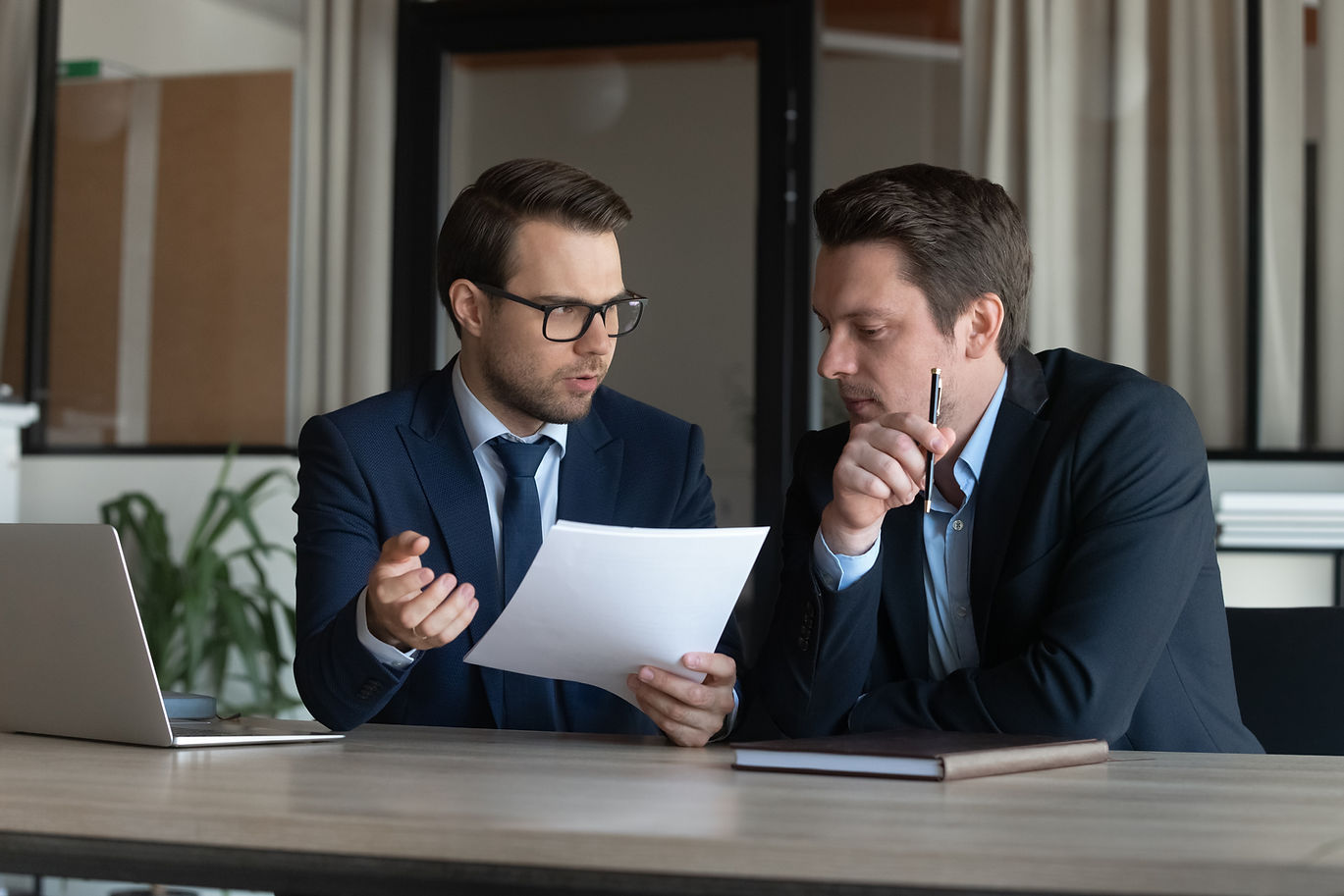 Serious young man supervisor analyse financial report of responsible worker pay attention