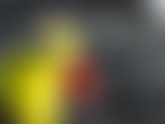 Someone places a bright yellow vinyl on the side of a black car. They are using a tool to smooth the wrap over the vehicle.