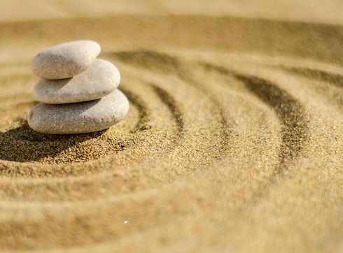 Three stacked white rocks surrounded by a ripple of sand in a zen garden