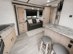 Rear living room in the Coachmen Spirit Ultra Lite featuring sofa, storage, and breakfast bar layout