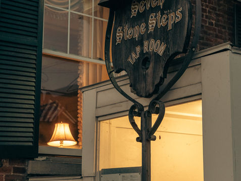 Sign for "Seven Stone Steps Tap Room" outside building.