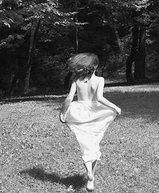 a person in a dress running in a grassy