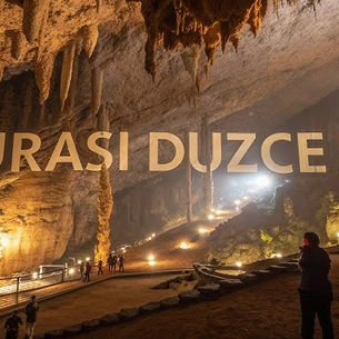 Düzce'deki doğal mağara iç mekanı. Sarkıt oluşumları, aydınlatılmış yürüyüş yolu ve ziyaretçiler. Faruk Özlü'nün Türkiye'nin en iyi mağaraları arasında gösterdiği Düzce mağarası.