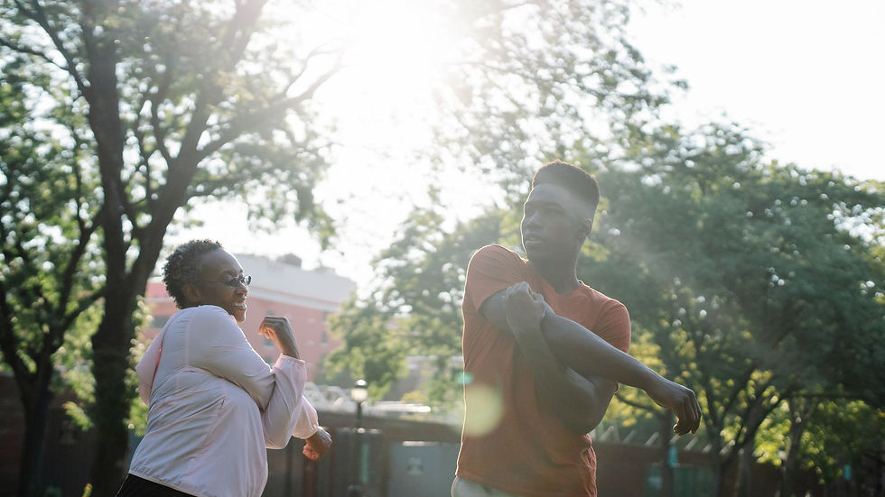 Joyful mother and son stretching together in a park on a sunny day, enjoying fitness and bonding.