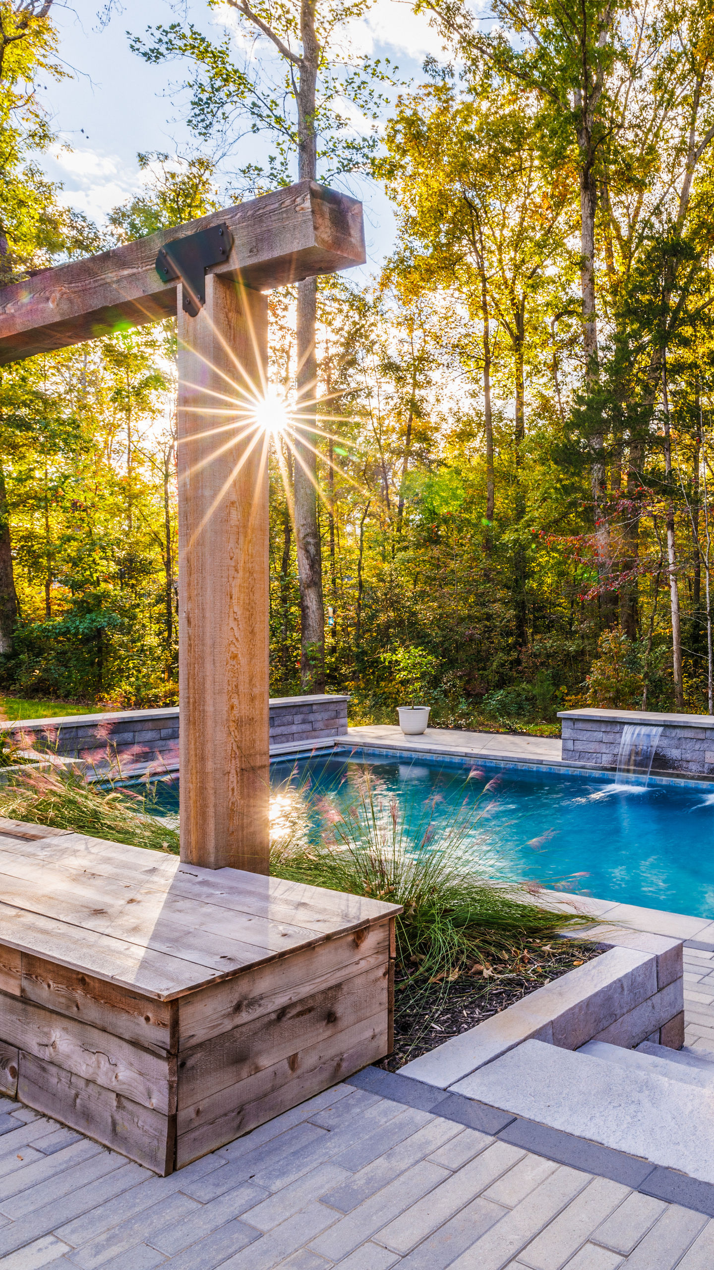 the sun is shining through the trees over a swimming pool