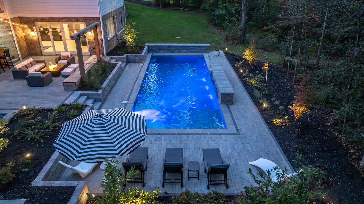 a large swimming pool with a striped umbrella in front of it
