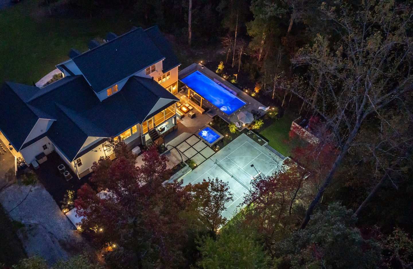 an aerial view of a house with a large pool and tennis court