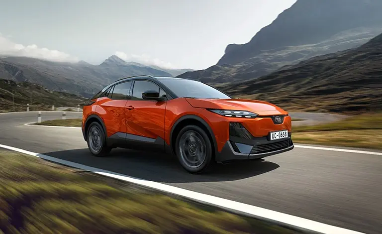 Nové kompaktné elektrické SUV Subaru Uncharted v oranžovej farbe Sun Blaze Pearl počas dynamickej jazdy. Exkluzívne v ponuke autorizovaného predajcu Remesloservis Nitra.