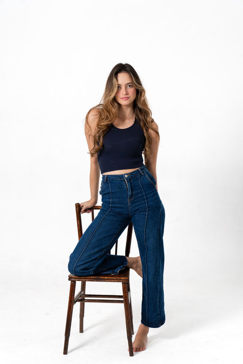 Mujer joven con outfit casual sentada sobre silla en estudio de Barcelona.