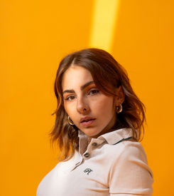 Mujer posando en fondo naranja durante sesión de book editorial lifestyle.