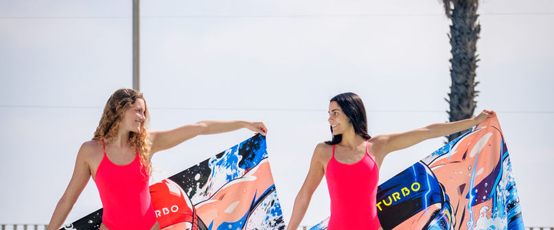Dos deportistas con tablas de natación junto a una piscina