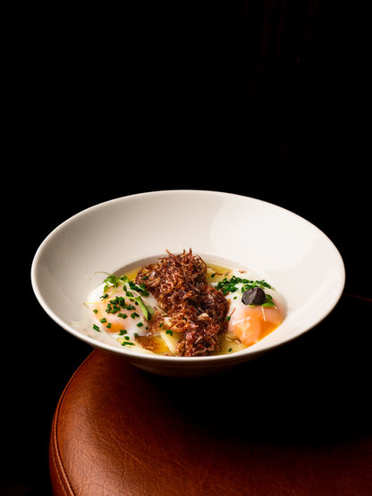 Plato de restaurante servido en vajilla blanca sobre un fondo negro.