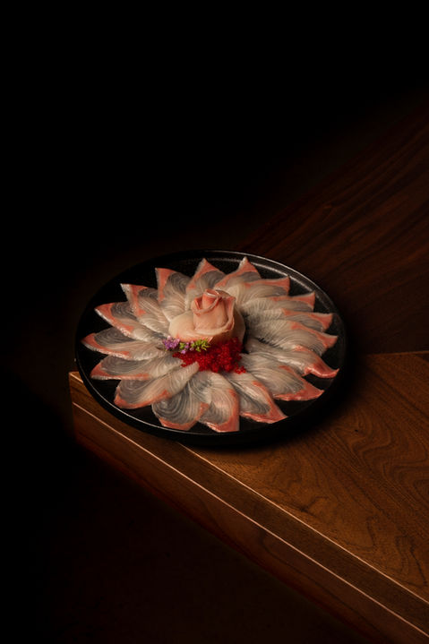Carpaccio de pescado en plato oscuro, fotografía gastronómica