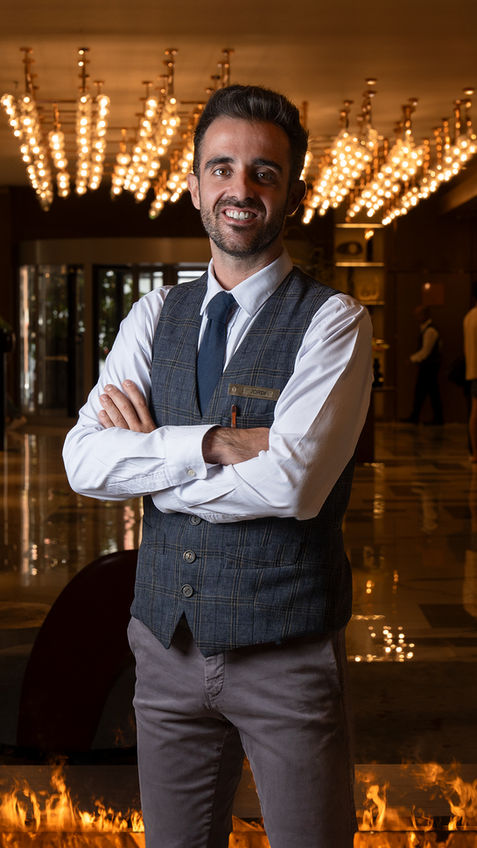 Bartender elegante posando con luces de fondo en Barcelona.