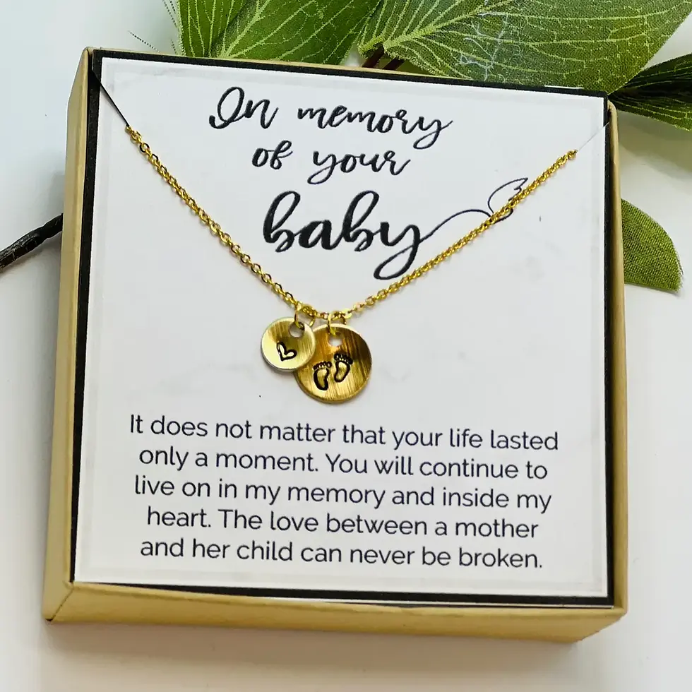 gold necklace with stamped charms - baby footprints and a heart. Set on display card "In memory of your baby"