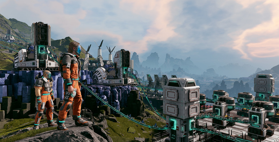 Two players in orange suits stand on a rocky cliff overlooking a massive industrial base. Glowing blue power lines connect various high-tech buildings and towers across the valley.