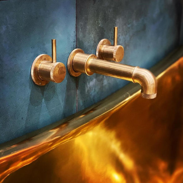 Gold faucet and handles on a blue wall in a modern style bathroom