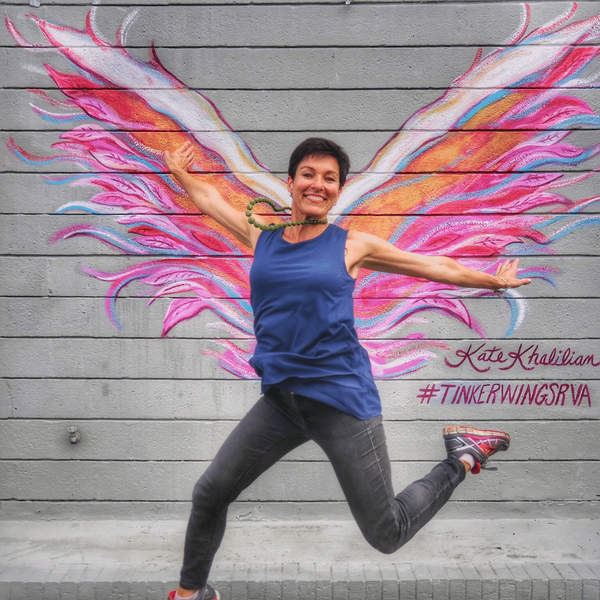 Kate Khaliian dances in front of her angel win mural a Tinker's in Richond Virginia
