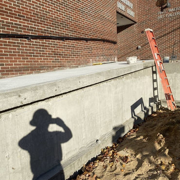 "Concrete foundation wall beside a brick art gallery