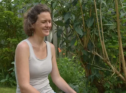 Judith Meinken fröhlich und mit sich verbunden in der Natur sitzend