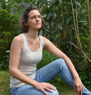 Judith Meinken eher ernst schauend in der Natur sitzend